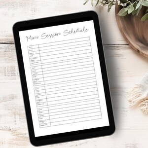 May include: A black tablet computer with a white screen displaying a "Mini Session Schedule" form with fields for name, phone, address, email, number of people, and session time.