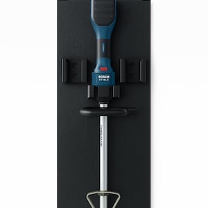 Könnte beinhalten: Schwarze Wandhalterung mit blauem und schwarzem Elektrowerkzeug und Zubehör. Der Text "MST" und "WANDHALTERUNG BOSCH GRT 18V-33" sind sichtbar. Das Werkzeug ist auf einer schwarzen rechteckigen Basis montiert.