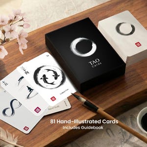 May include: A black box of "TAO Cards" with a white circular design and a stack of cards with black and white illustrations. The cards feature Chinese characters and the text "Endless Flow" and "Way of Truth". A paintbrush is also visible in the image.