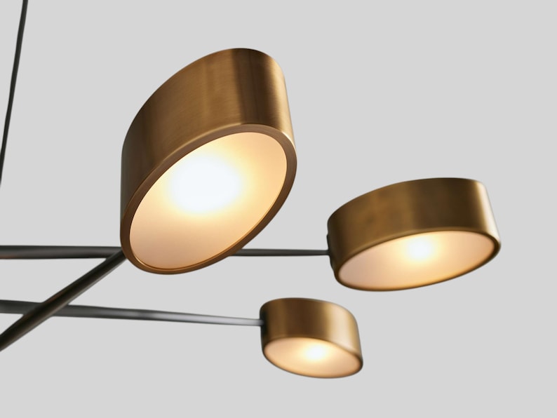 May include: A modern, multi-light chandelier with a black metal frame and gold-toned, oval-shaped light fixtures. The light fixtures have frosted glass diffusers.