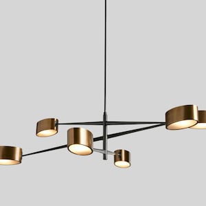 May include: A modern, black and gold chandelier with five lights. The lights are arranged in a geometric pattern and have a unique, curved shape.