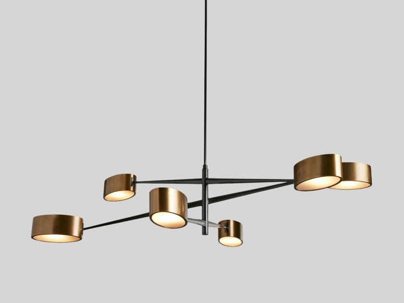 May include: A modern, black and gold chandelier with five lights. The lights are arranged in a geometric pattern and have a unique, curved shape.