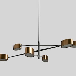 May include: A modern chandelier with five gold-toned light fixtures and black metal arms. The chandelier has a minimalist design and is suspended from a single black cord.