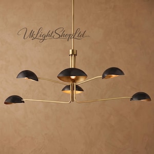 May include: A multi-arm chandelier featuring a central brass rod and five extending arms. Each arm holds a matte black dome-shaped shade with a gold interior finish. The text "UkLightShopLtd" is visible in the upper left portion of the image.