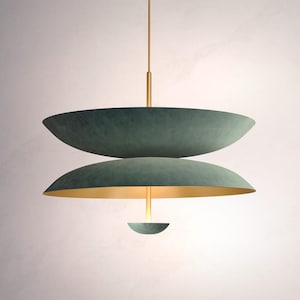 Peut inclure: Un luminaire suspendu moderne à trois niveaux avec une finition en métal vert et un accent doré. La lumière est suspendue à un seul cordon.