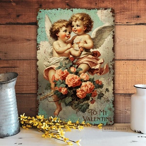 May include: Vintage-style metal sign featuring two cherubs with wings, holding a bouquet of pink roses. The sign has a distressed, rustic look and reads "To My Valentine" at the bottom.