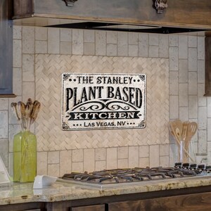 Op de afbeelding: Een zwart-wit bord met de tekst "The Stanley... Plant Based Kitchen... Las Vegas, NV..." op een witte betegelde keukenachterwand.