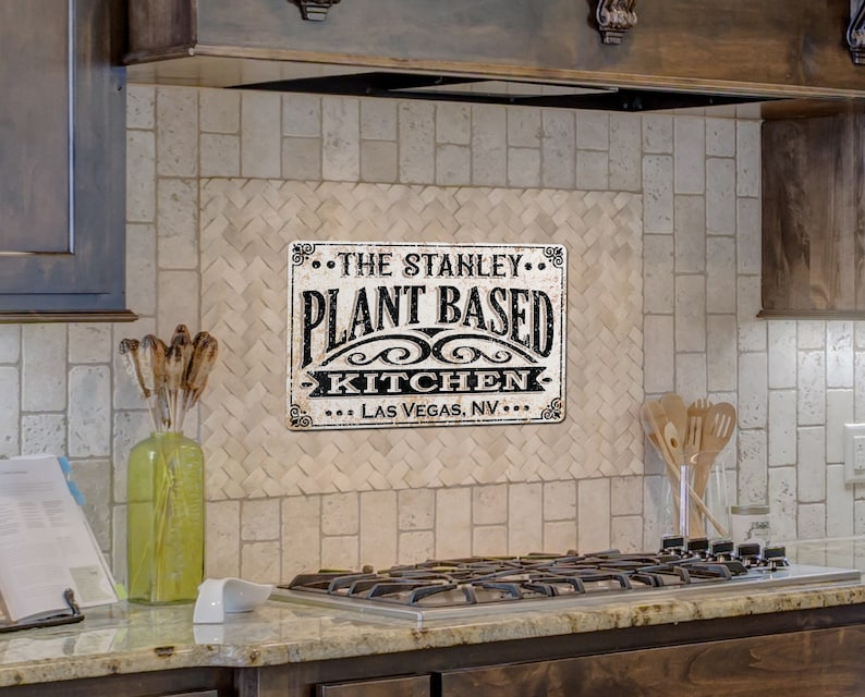 Op de afbeelding: Een zwart-wit bord met de tekst "The Stanley... Plant Based Kitchen... Las Vegas, NV..." op een witte betegelde keukenachterwand.