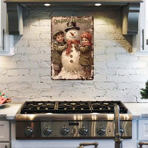 May include: A vintage-style metal sign with a Christmas theme. It features a snowman with two children, one on each side, and the text "Seasons Greetings".