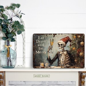 May include: A metal sign with a distressed, rusty look featuring a skeleton wearing a Santa hat and holding a glass of champagne. The sign reads "Eat, Drink and be Merry".