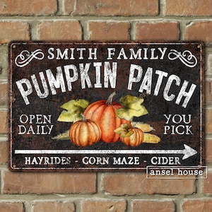 May include: A black metal sign with white text that reads "Smith Family Pumpkin Patch". The sign has a rustic look and features a drawing of pumpkins and corn. The text "Open Daily" and "You Pick" are also on the sign. The sign also has the text "Hayrides - Corn Maze - Cider" and "ansel house".