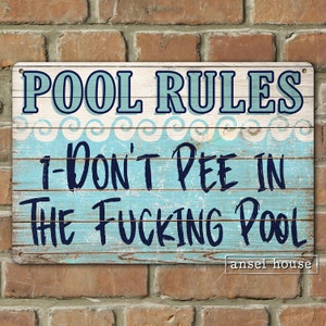 May include: A blue and white wooden sign with the text "POOL RULES" and "I-DON'T PEE IN THE FUCKING POOL" in black lettering. The sign has a distressed wood look and a white wave pattern.