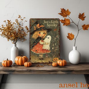 May include: A vintage-style metal sign with the text "Just a Little Spooky" featuring a cartoon girl in a witch hat holding a ghost. The sign is displayed on a wooden table with pumpkins and fall foliage in vases.