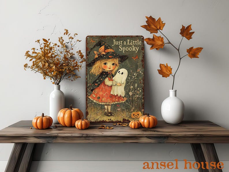 May include: A vintage-style metal sign with the text "Just a Little Spooky" featuring a cartoon girl in a witch hat holding a ghost. The sign is displayed on a wooden table with pumpkins and fall foliage in vases.