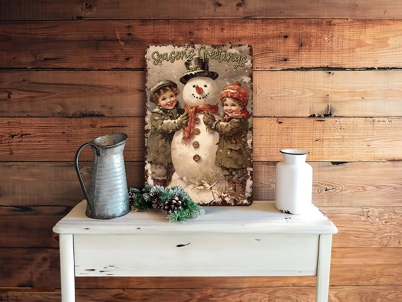 May include: A vintage-style Christmas sign featuring a snowman with two children. The sign has a red, white, and green color scheme and says "Seasons Greetings".