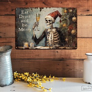 May include: A metal sign with a distressed, vintage look featuring a skeleton wearing a Santa hat and holding a glass of champagne. The sign reads "Eat, Drink and be Merry".