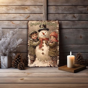 May include: A vintage-style metal sign with a snowman and two children. The sign reads "Seasons Greetings".