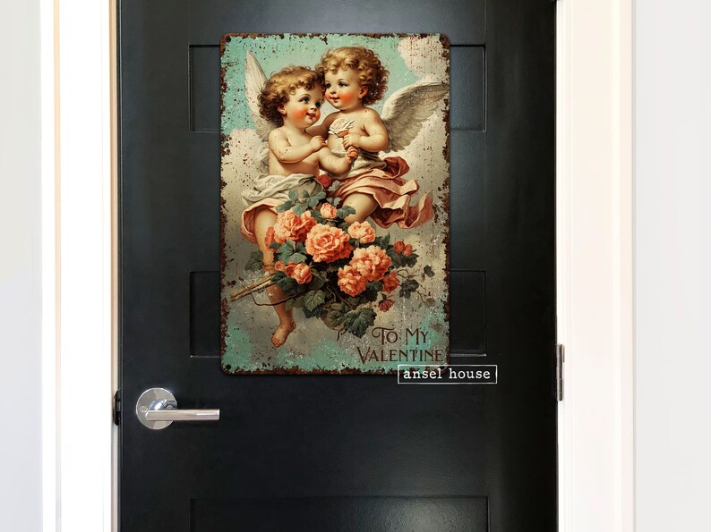 May include: Vintage-style metal sign featuring two cherubs with wings, holding a bouquet of pink roses. The sign has a distressed, rusty look and reads "To My Valentine" with the text "ansel house" below.
