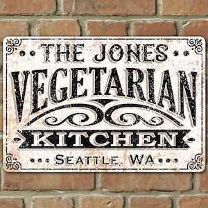 May include: A white metal sign with black text that reads "... THE JONES ... VEGETARIAN KITCHEN ... SEATTLE, WA ..." The sign has a distressed, vintage look.