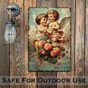 May include: Vintage-style metal sign featuring two cherubs with wings, holding a bouquet of pink roses. The sign has a distressed, aged look and reads "To My Valentine".