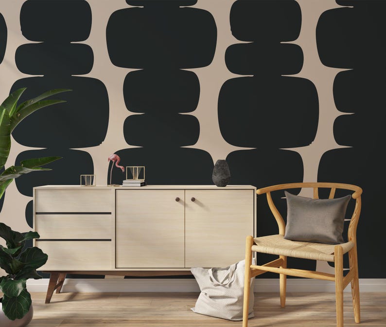 Peut inclure: Un mur beige avec un motif abstrait noir et blanc. Une chaise en bois avec un si&egrave;ge en osier et un coussin gris est plac&eacute;e devant un meuble en bois clair avec deux tiroirs et deux portes.