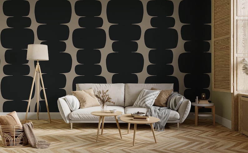 Peut inclure: Un salon avec un canap&eacute; blanc et un papier peint &agrave; motifs g&eacute;om&eacute;triques noirs et beiges. Le canap&eacute; est dot&eacute; de coussins et d'une couverture. Il y a deux tables basses devant le canap&eacute;. Un lampadaire se trouve dans le coin de la pi&egrave;ce.