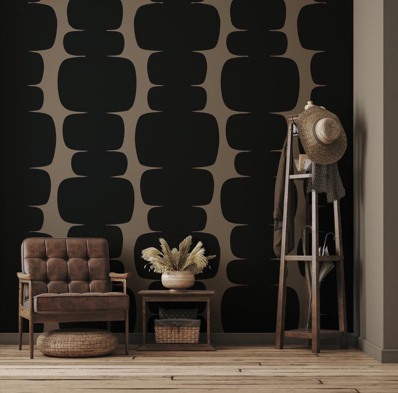 Peut inclure: Un int&eacute;rieur de salon avec un fauteuil en cuir marron, une petite table d'appoint en bois avec un panier en osier et un porte-manteau en bois avec un chapeau de paille et une &eacute;charpe. Le mur est recouvert d'un papier peint avec un motif g&eacute;om&eacute;trique de formes arrondies noires et brunes.
