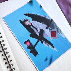 Könnte beinhalten: Kunstdruck mit einer Figur mit schwarzen Flügeln, roten Hörnern und einem weißen Mantel vor blauem Himmel. Das Kunstwerk zeigt eine Ampel mit rotem Licht und ein Straßenschild. Der Druck wird auf einer weißen Oberfläche angezeigt.