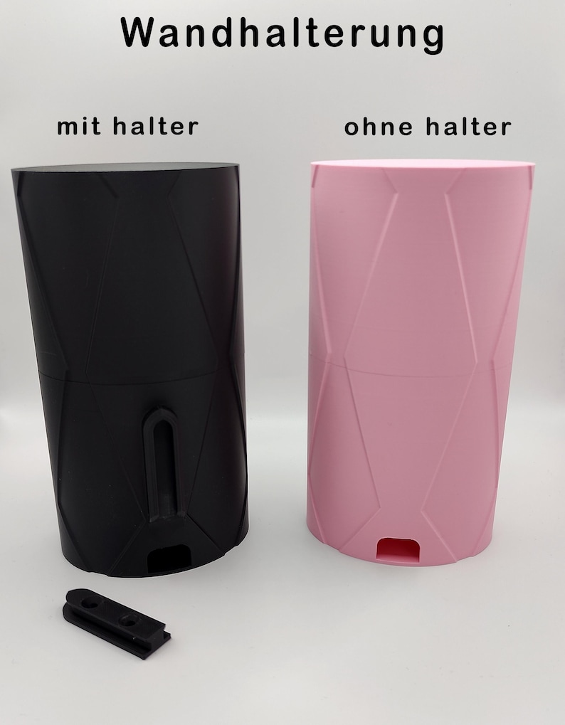 May include: Two wall mounts, one black and one pink, with a geometric pattern. The black wall mount has a holder attached to it. The pink wall mount does not have a holder. The text "Wandhalterung" is at the top of the image. The text "mit halter" is below the black wall mount. The text "ohne halter" is below the pink wall mount.