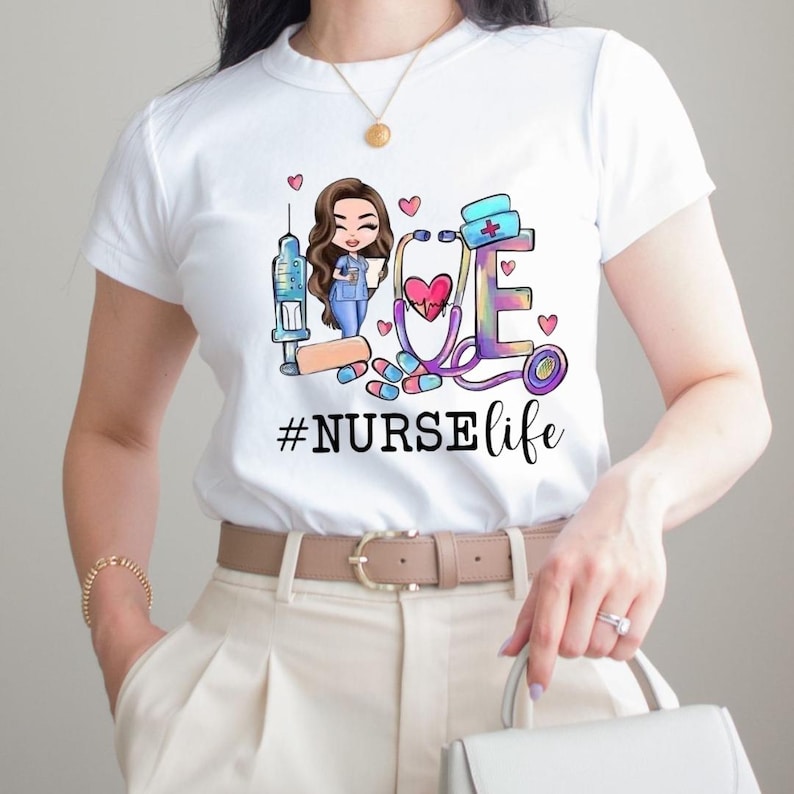 May include: White t-shirt with a colourful graphic design. The design spells "LOVE" with medical illustrations, including a nurse, syringe, stethoscope, and pills. The text "#NURSElife" is below the design.