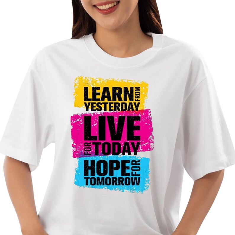 May include: White t-shirt with the text "LEARN FROM YESTERDAY, LIVE FOR TODAY, HOPE FOR TOMORROW" in black letters on top of three colorful rectangular blocks: yellow, pink, and blue.