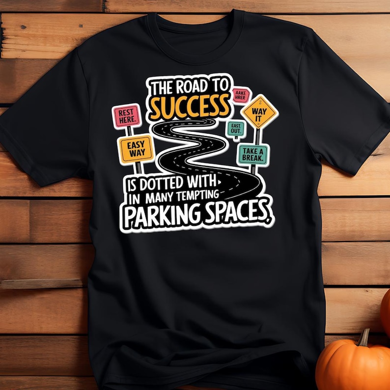 May include: Black t-shirt with a humorous graphic. The design features a winding road labeled "The Road to Success" dotted with signs like "Easy Way" and "Parking Spaces." The text is in white, yellow, and green.