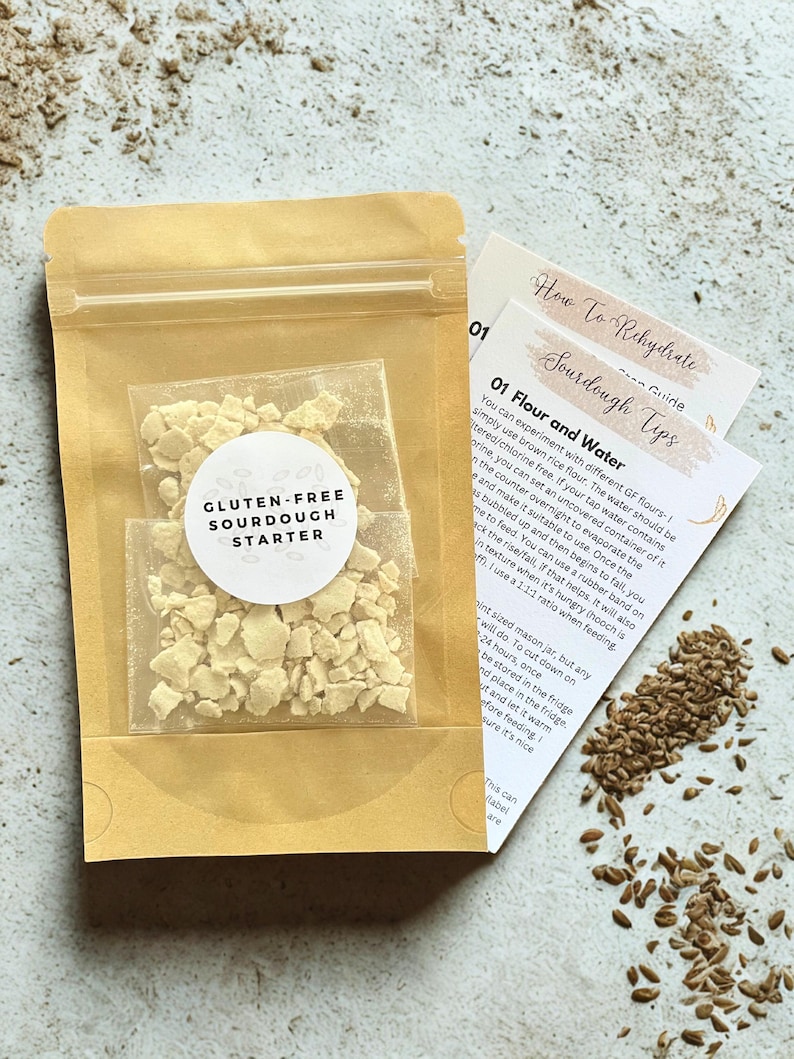 May include: A package containing gluten-free sourdough starter, with a clear window showing the dried starter. The package is in a tan paper envelope. Instructions on rehydrating sourdough are included.