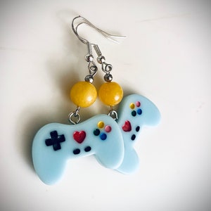 May include: A pair of light blue gamer controller earrings with yellow beads and silver hooks.