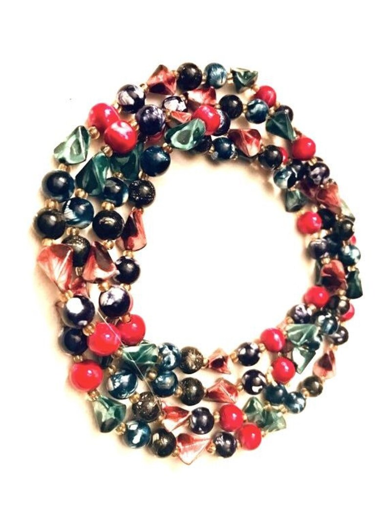 May include: A multi-strand necklace made of colorful glass beads. The beads are in shades of red, green, blue, and black. Some of the beads are round, while others are triangular.
