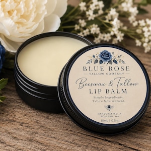 Puede incluir: Una lata de metal negro con bálsamo labial color crema, con una tapa que muestra una ilustración de una rosa azul y el texto: BLUE ROSE TALLOW COMPANY, Beeswax & Tallow LIP BALM, Simple Ingredients, Tallow Nourishment, 15ml | 0.5 oz, Handcrafted in Poulsbo, WA.