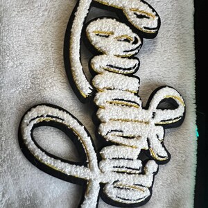 May include: White fluffy patch with a gold outline, shaped like the word "Love" in a cursive font.