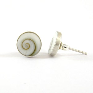 May include: A pair of silver stud earrings with a white and brown shell inlay. The shell has a spiral pattern.
