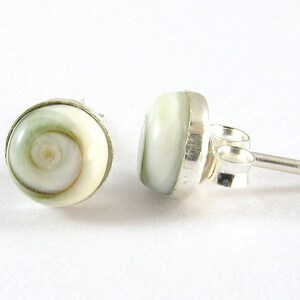 May include: A pair of silver earrings featuring a white and green shell design. The shell has a spiral pattern.