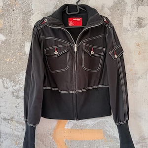 May include: Black jacket with white stitching, two front pockets, and a zip closure. The jacket has a ribbed hem and cuffs, and red accents on the shoulders. The label reads "MISS PISH".