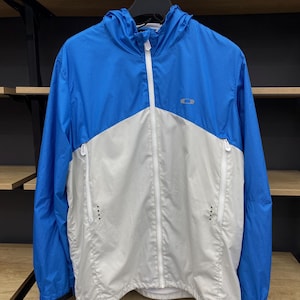 K&ouml;nnte beinhalten: Eine blaue und wei&szlig;e Kapuzenjacke mit Rei&szlig;verschluss. Die Jacke hat ein kleines Logo auf der Brust.