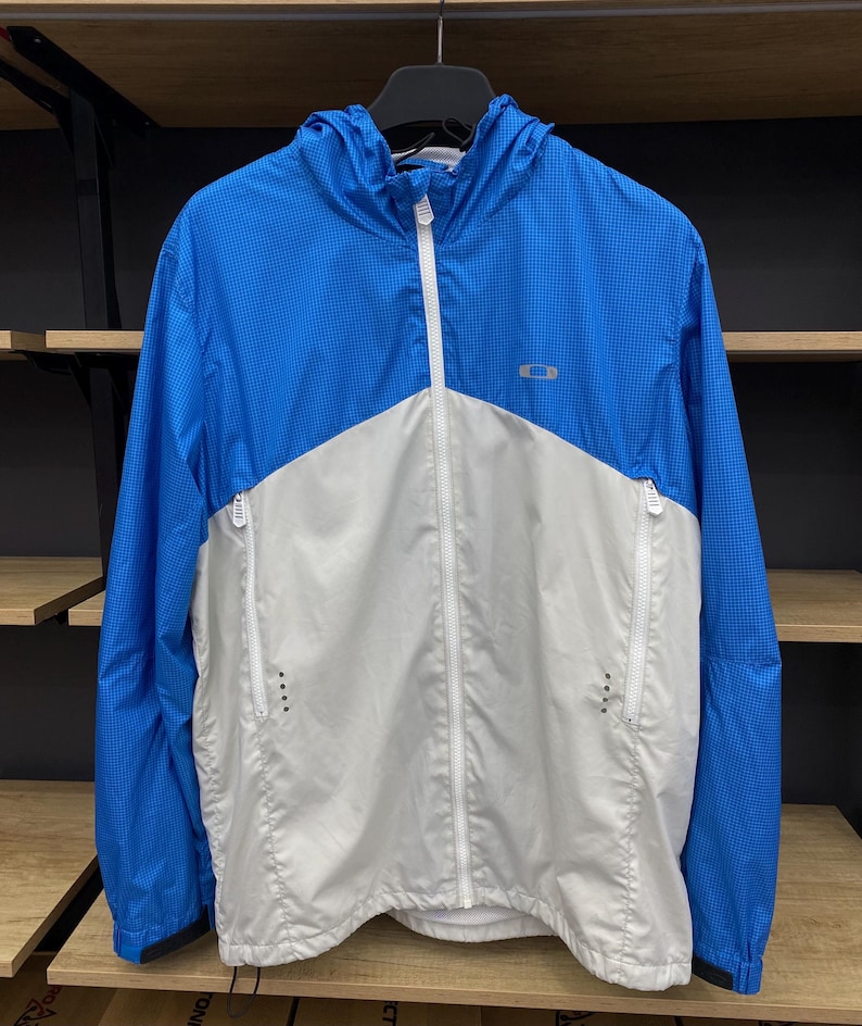 K&ouml;nnte beinhalten: Eine blaue und wei&szlig;e Kapuzenjacke mit Rei&szlig;verschluss. Die Jacke hat ein kleines Logo auf der Brust.