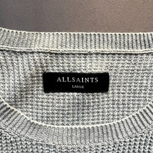 May include: A gray knitted sweater with a black label that reads "ALLSAINTS LARGE".