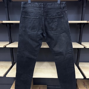 May include: Black denim jeans with a small square patch on the back right pocket.