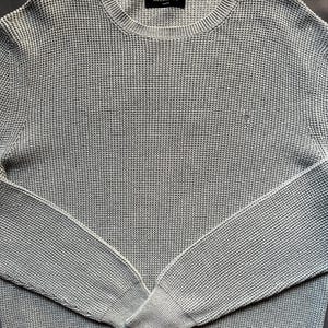 May include: A light gray waffle knit sweater with a crew neck and long sleeves. The sweater has a small "AllSaints" label on the front.