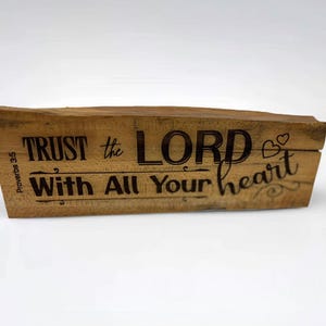 May include: A wooden block with the words "TRUST the LORD With All Your heart" engraved in black. The block has a natural wood grain finish and includes the Bible verse Proverbs 3:5.