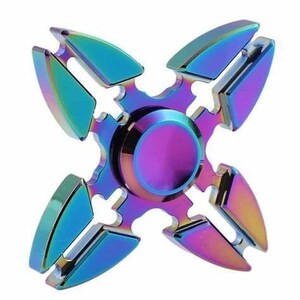 Pode incluir: Um fidget spinner multicolorido com acabamento metálico. O spinner tem quatro lâminas e um centro circular. As cores mudam de azul para roxo para dourado, criando um efeito arco-íris. O design é simétrico e moderno.