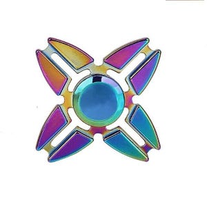 Könnte beinhalten: Ein mehrfarbiger Fidget Spinner mit einem vierblättrigen Kleeblatt-Design. Der Spinner hat einen zentralen blauen Kreis, umgeben von vier Flügeln in Lila-, Gold- und Türkistönen. Das metallische Spielzeug ist zum Drehen konzipiert.