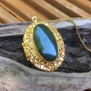 May include: A gold locket necklace with a green oval stone set in a filigree design.