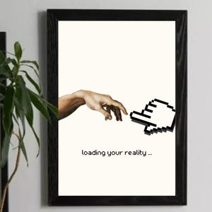 以下が含まれることがあります： 黒いフレームに入ったアートプリント。クリーム色の背景に、ピクセル化されたカーソルに手を伸ばしている様子が描かれています。「loading your reality...」というテキストが下にあります。